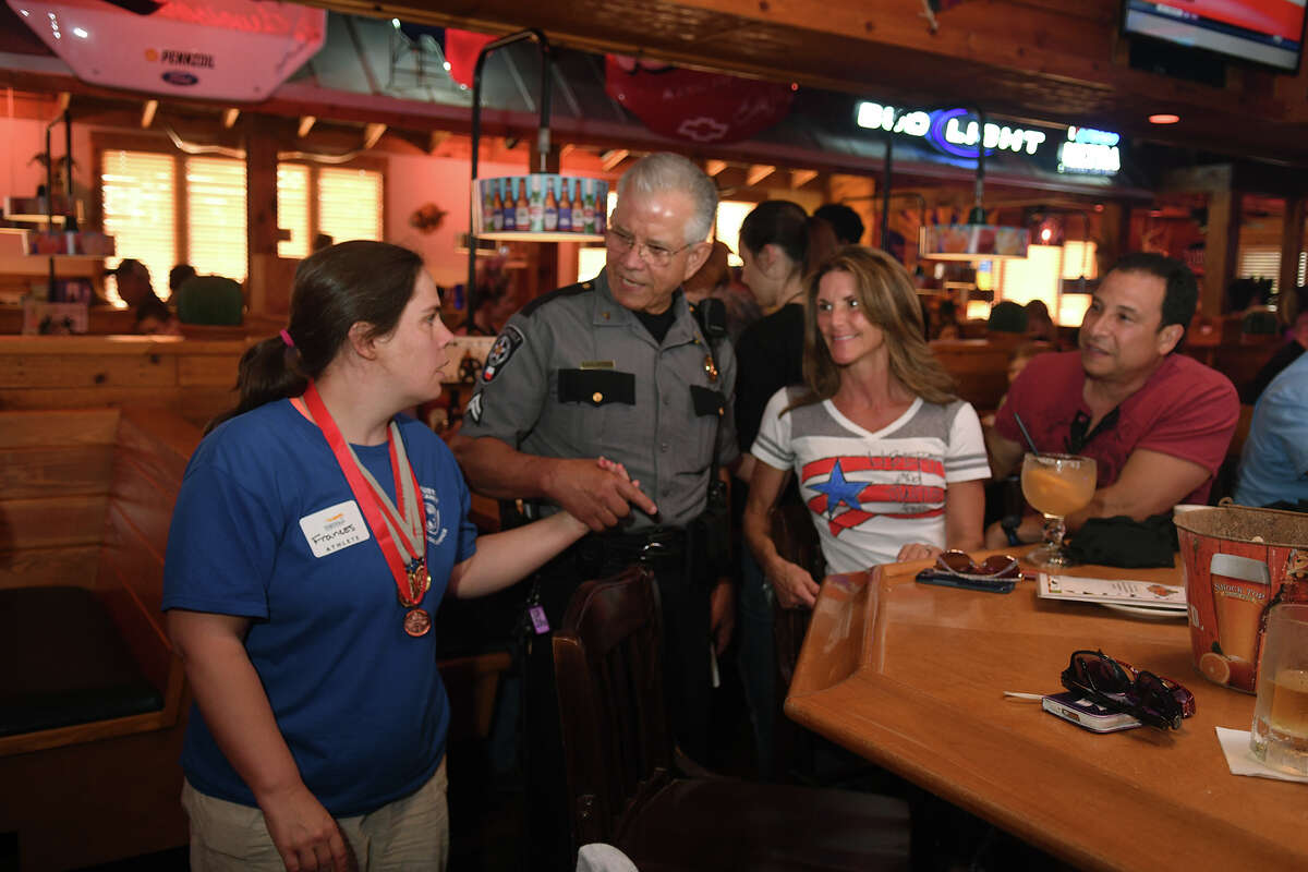 Gene Barnett, center, from Precinct 4 Constable's Office, introduces Special Athlete Frances, left, to Dody and Ricky Pedraza, right, of Kingwood, whose son Jake is on the Special Olympics swim team, during the Tip-A-Cop event at Texas Roadhouse in Kingwood on July 27, 2017. (Photo by Jerry Baker/Freelance)