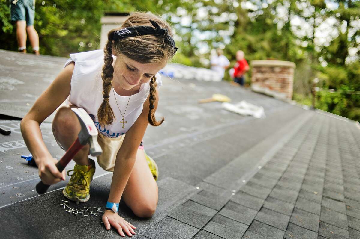 Riley Mathers of Virginia works to retile the roof of Ruth Laatsch at E. David Road on Monday, July 24, 2017 as part of the Call to the Creek group work project, which brings hundreds of high school and college students from around the country to do volunteer work in the Midland area.