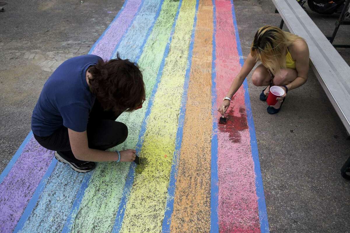 Volunteers Michelle Cowan, left, and Alize Sanchez use chalk to create rainbow crosswalks in honor of Pride at the intersection of Evergreen and Main streets in San Antonio, Texas on July 1, 2017.
