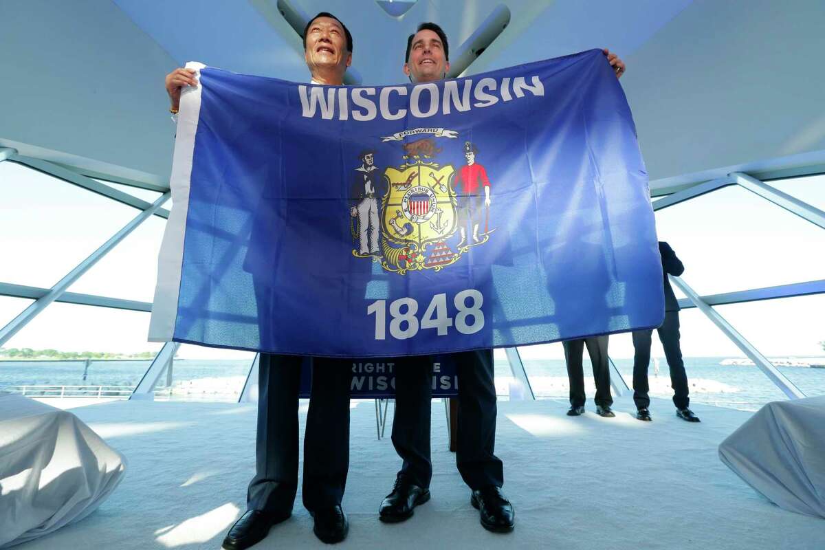 Foxconn Chairman Terry Gou, left, and Gov. Scott Walker hold the Wisconsin flag to celebrate their $10 billion investment to build a display panel plant in Wisconsin, at the Milwaukee Art Museum in Milwaukee, Wis., Thursday, July 27, 2017. (Mike De Sisti/Milwaukee Journal-Sentinel via AP) ORG XMIT: WIMIL401