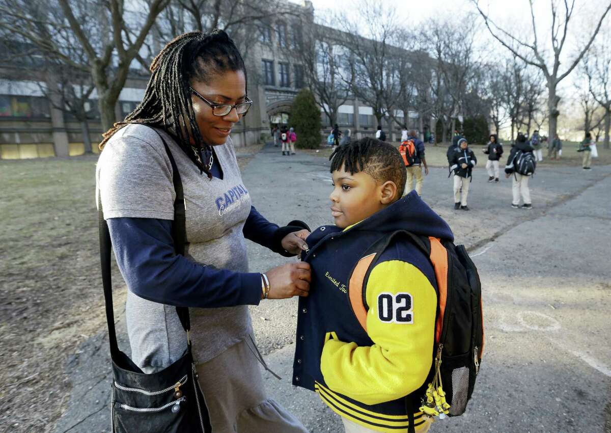 In this Feb. 23, 2017, photo, Natalie Langlaise snaps the jacket of her son Justin outside the Martin Luther King Jr. Elementary School in Hartford, Conn. The city of Hartford has been hailed nationally as a school choice success story. Its magnet schools have promoted racial integration and new levels of academic achievement. For traditional public schools, such as Martin Luther King Jr., it’s a different story.