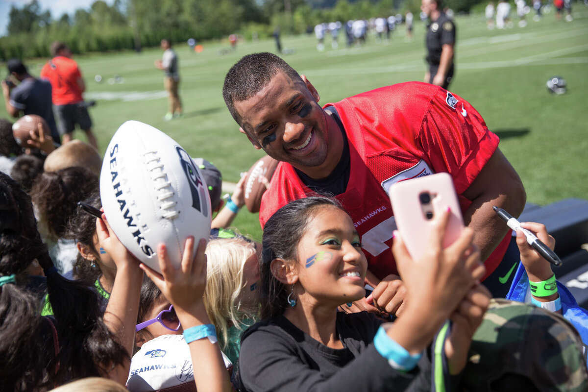 Quarterback Russell Wilson poses for a selfie with a young fan following the first day of practice on Sunday, July 30, 2017.