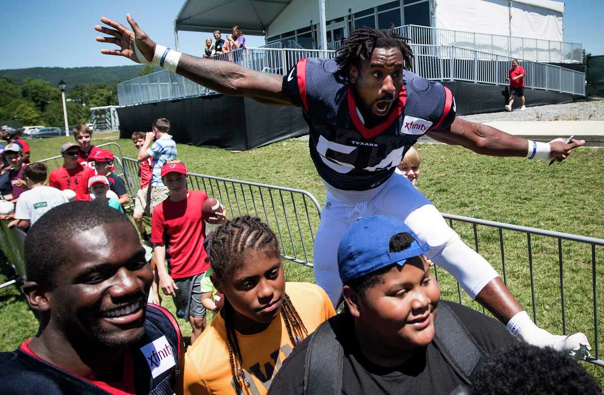 Houston Texans linebacker Sio Moore (54) jumps into the background of a photo linebacker Shakeel Rashad, far left, is taking with a group of young fans during training camp at the Greenbrier on Sunday, July 30, 2017, in White Sulphur Springs, W.Va.