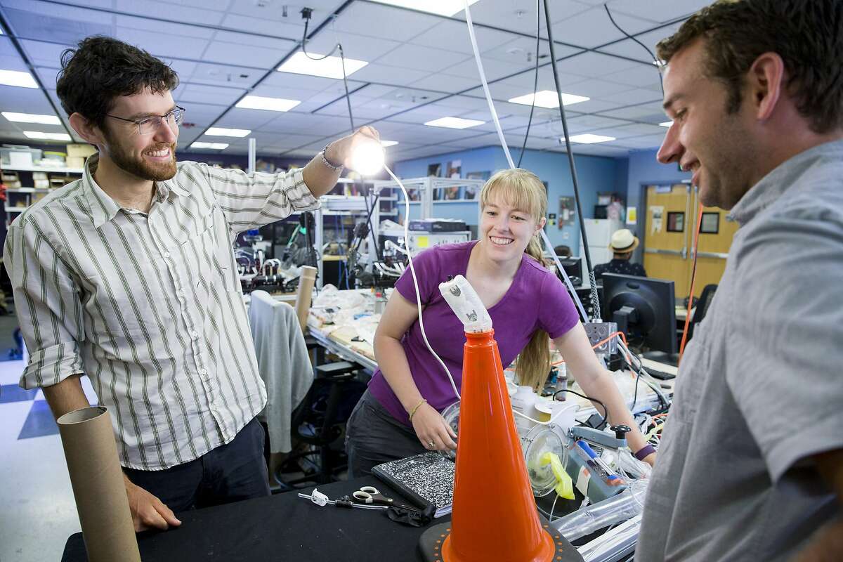 From left: UC Santa Barbara assistant professor and mechanical engineer Elliot Hawkes with Stanford graduates Laura Blumenschein and Joey Greer demonstrate how the vine-like robot grows and navigates through the hole of the orange cone at the Mechanical Engineering Research Lab on Friday, July 28, 2017, in Stanford, Calif. One of the applications the robot may be used for is search and rescue. With it's exterior made out of a low-density polyethylene plastic, the robot may navigate through clutter and squeeze through places deemed too dangerous or small for humans. The robot moves and grows with controlled air pressure.