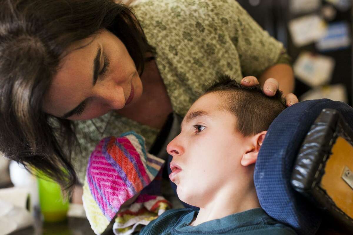 Liz Tullis talks to her son Conrad, 12, after he was fed in April 2015. Tullis raised funds for a study at UT Health San Antonio that suggests brain injury in children who suffer near-fatal drownings might just affect areas in the brain involving movement, leaving networks related to hearing, sight and social awareness intact.