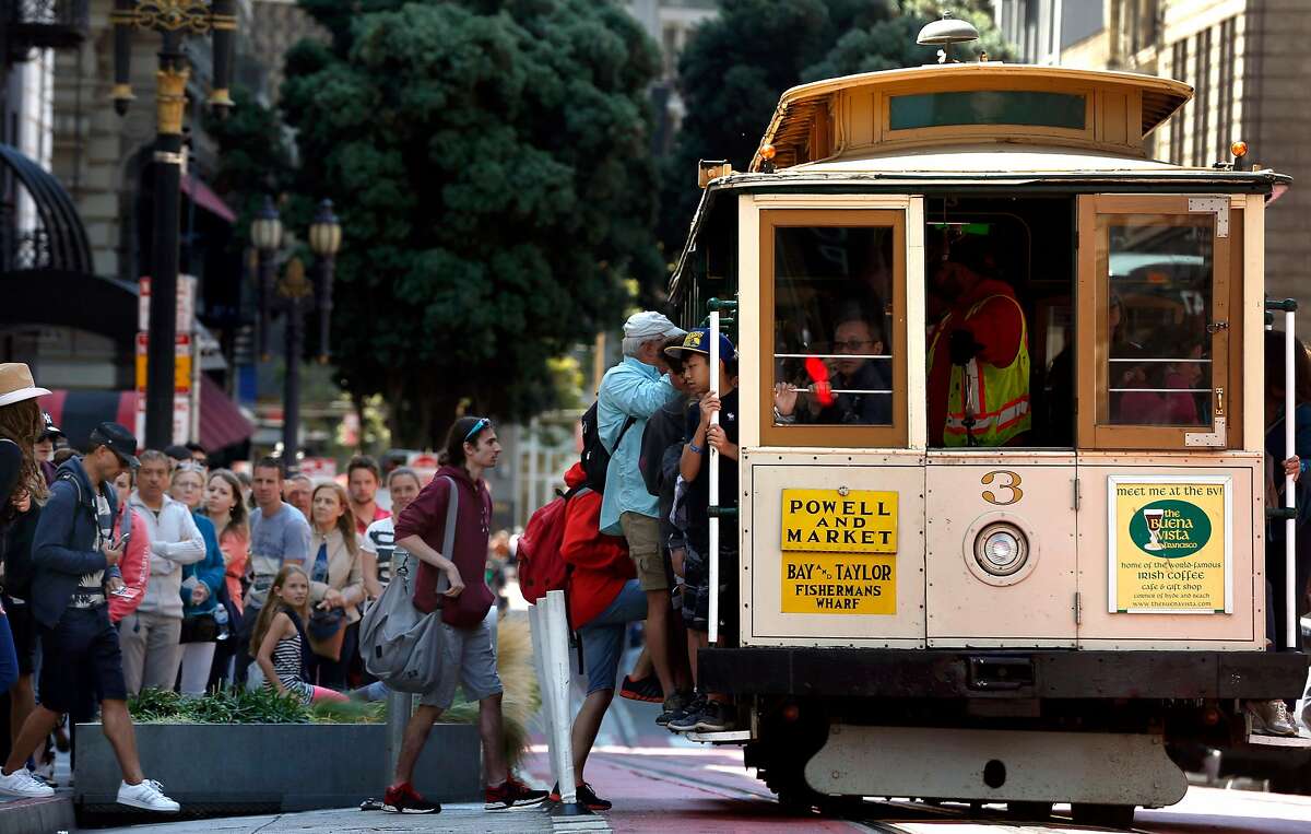 Passengers wait in line to board a cable car at Powell and O'Farrell streets in San Francisco.