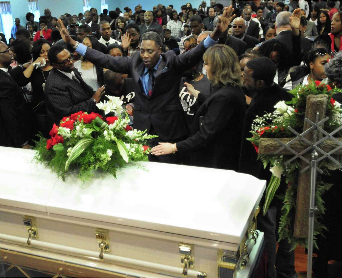(Peter Hvizdak — Register) Gregory Fulcher, Sr. of West Haven, stands over the coffin of his daughter Erika Renee Robinson, 26, during an altar call at her funeral Saturday November 2, 2013 at the Agape Christian Center in New Haven, Conn. Robinson was the unintended victim of a shooting last week at the Key Club in New Haven, Conn.