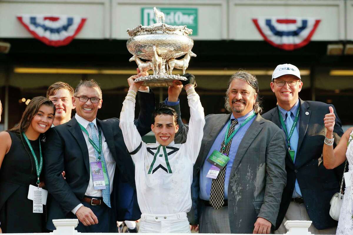 Jockey Javier Castellano, center, hoists the August Belmont Trophy as trainer Steve Asmussen, second from right, Winstar Farms president and C.E.O. Elliott Walden, right, and WinStar Farms principal owner Kenny Troutt, second from left, look on after their horse, Creator, won the 148th running of the Belmont Stakes horse race at Belmont Park, Saturday, June 11, 2016, in Elmont, N.Y.
