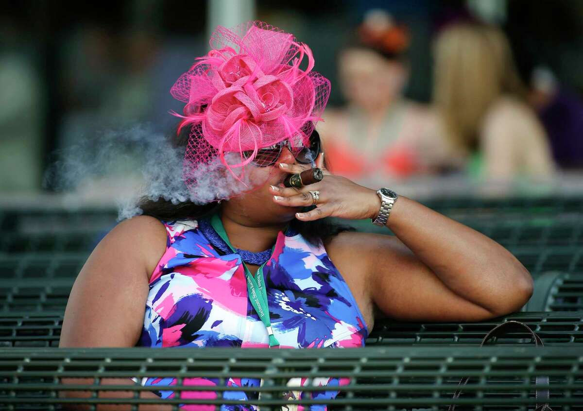 A horse racing fan enjoys a cigar at Belmont Park on Saturday, June 11, 2016, in Elmont, N.Y. The 148th running of the Belmont Stakes horse race will be held at the park later in the day.