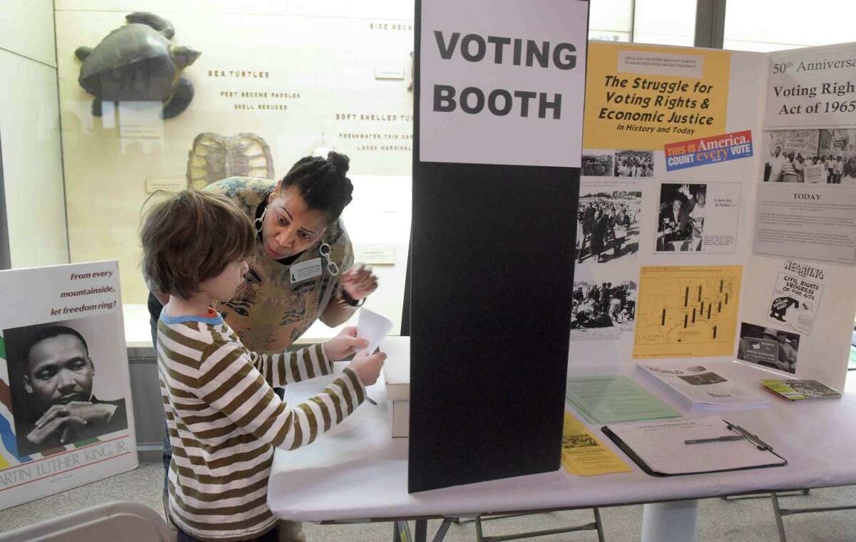 (Peter Hvizdak - New Haven Register) Lev Felson, 7, of New Haven, left, as Vanessa Glenn-Person of the New Haven People's Center explains the power of the vote and difference it makes at a mock voting booth During the 19th annual family festival "Dr. Martin Luther King, Jr.'s Legacy of Environmental and Social Justice" Sunday, January 16, 2015 at the Yale Peabody Museum of Natural History in New Haven.