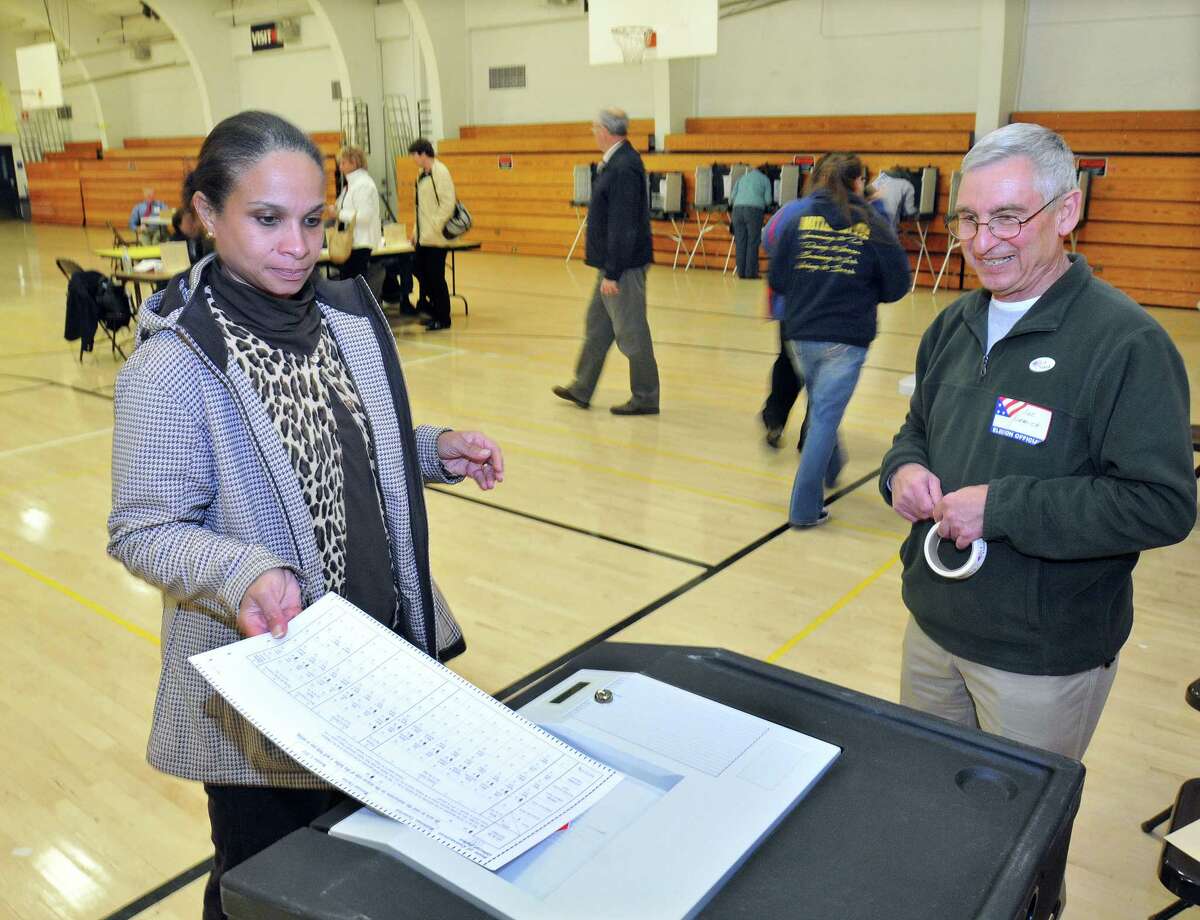 Renee Johnson-Thornton, a voter in Distrit 12 inserts her ballot into the optical scanner at Woodrow Wilson Middle School in Middletown Tuesday. Catherine Avalone - The Middletown Press