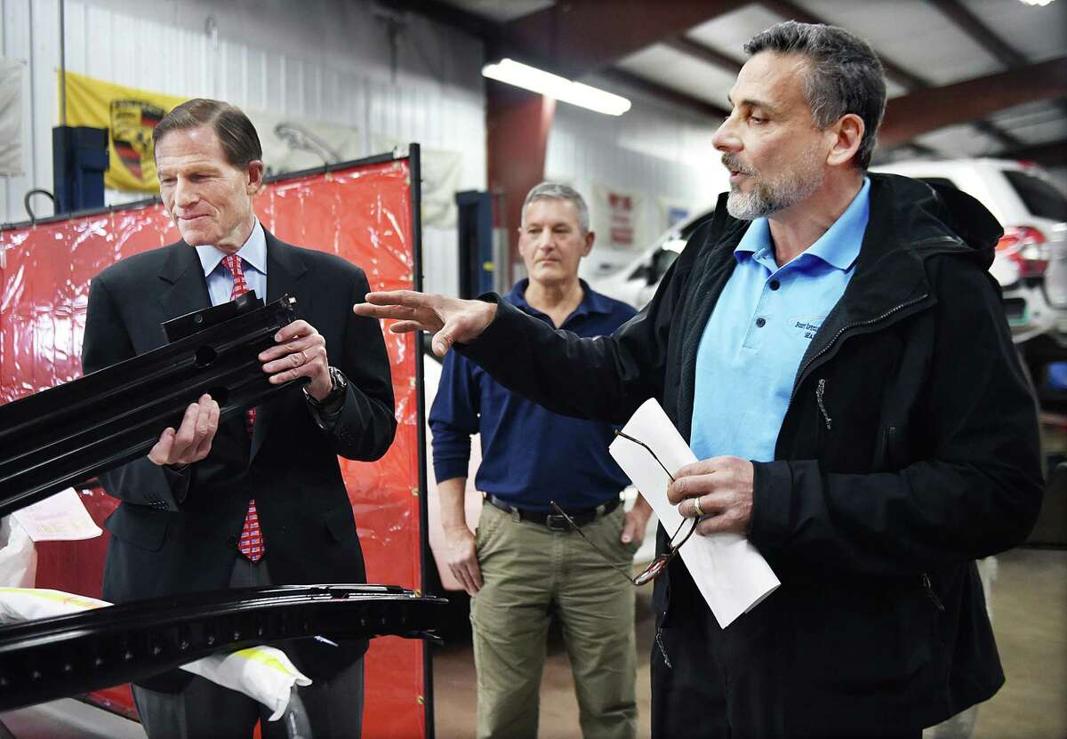 (Catherine Avalone - New Haven Register) Anthony Ferraiolo, President of the Auto Body Association of Connecticut (ABAC) and owner of A & R Body Specialty & Collision Works, Inc. in Wallingford explains the difference between a factory-made part and an imitation to U.S. Senator Richard Blumenthal (D-Conn.) examines an imitation which is sold for $90 less, but inferior to the part made by Ford, Saturday, February 28, 2015. Body shop owners demonstrated the differences in quality and performance between the parts and to remind consumers that they have the right to choose where to repair their vehicles, regardless of recommendations from their auto insurer.