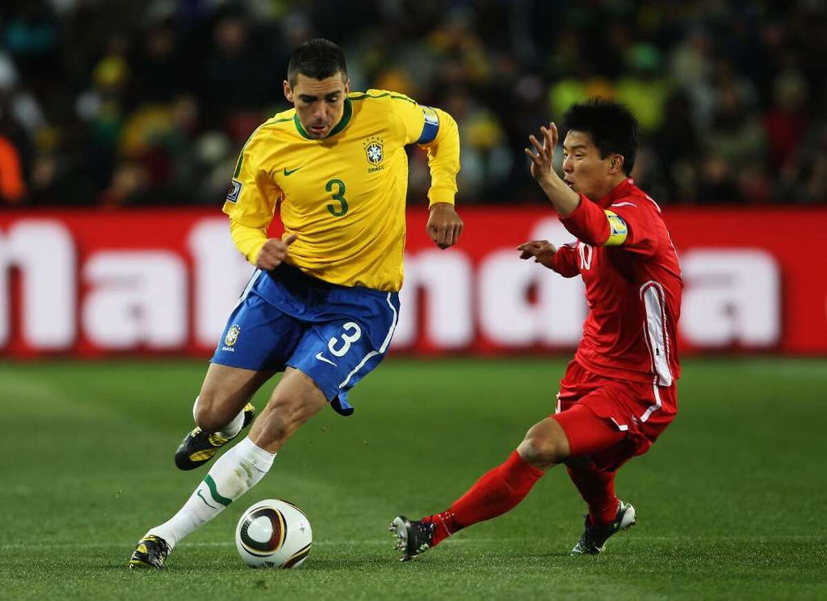 JOHANNESBURG, SOUTH AFRICA - JUNE 15: Lucio of Brazil is challenged by Hong Yong-Jo of North Korea during the 2010 FIFA World Cup South Africa Group G match between Brazil and North Korea at Ellis Park Stadium on June 15, 2010 in Johannesburg, South Africa. (Photo by Phil Cole/Getty Images) *** Local Caption *** Lucio;Hong Yong-Jo