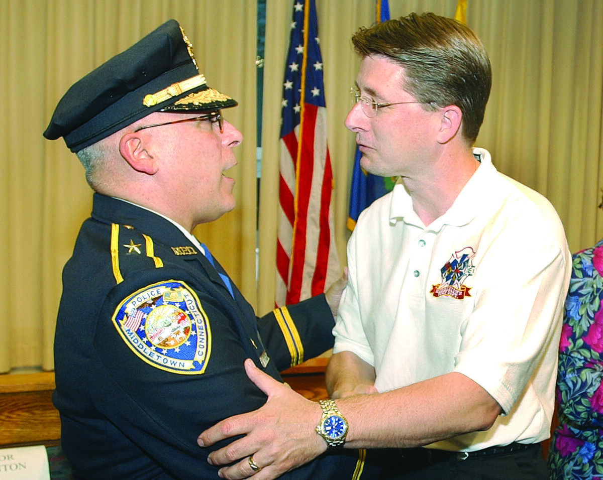 Deputy Chief of Police Philip Pessina (left) is congradulated by Robert Ross, chief of the Middletown Fire Department, after the Middletown Police Department Swearing In Ceremony Friday...photo by irena Pastorello..060603...web:MPchie.jpg
