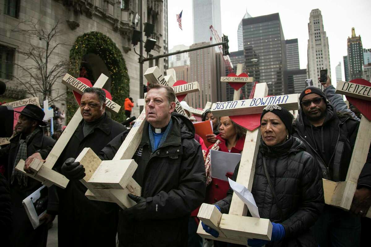 FILE - In this Dec. 31, 2016, file photo, the Rev. Jesse Jackson, Rev. Michael Pfleger, center, and state Sen. Jacqueline Collins, right, lead hundreds in a march down Michigan Avenue, carrying crosses for all those killed by Chicago violence in 2016. President-elect Donald Trump said Chicago Mayor Rahm Emanuel should ask for federal help if he isn't able to bring down a homicide count that soared last year. Trump isn't the first to broach the idea that the U.S. government could do more to stem violence in Chicago. But what more it can do isn't at all clear.
