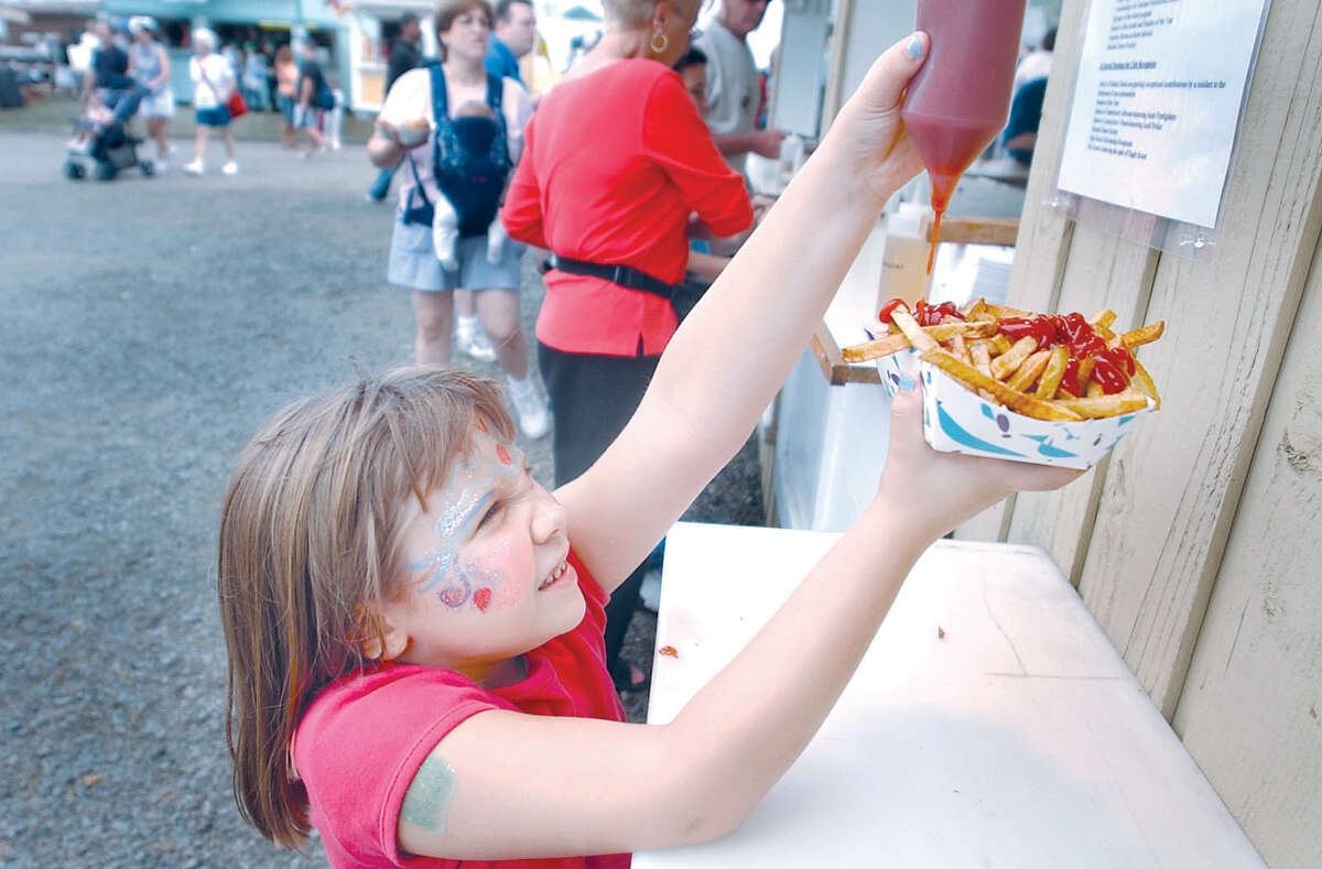 Samantha Seco,7, reaches up for a squirt of ketchup on her french fries Saturday during the Durham Fair......J. Rossi photo........092703.