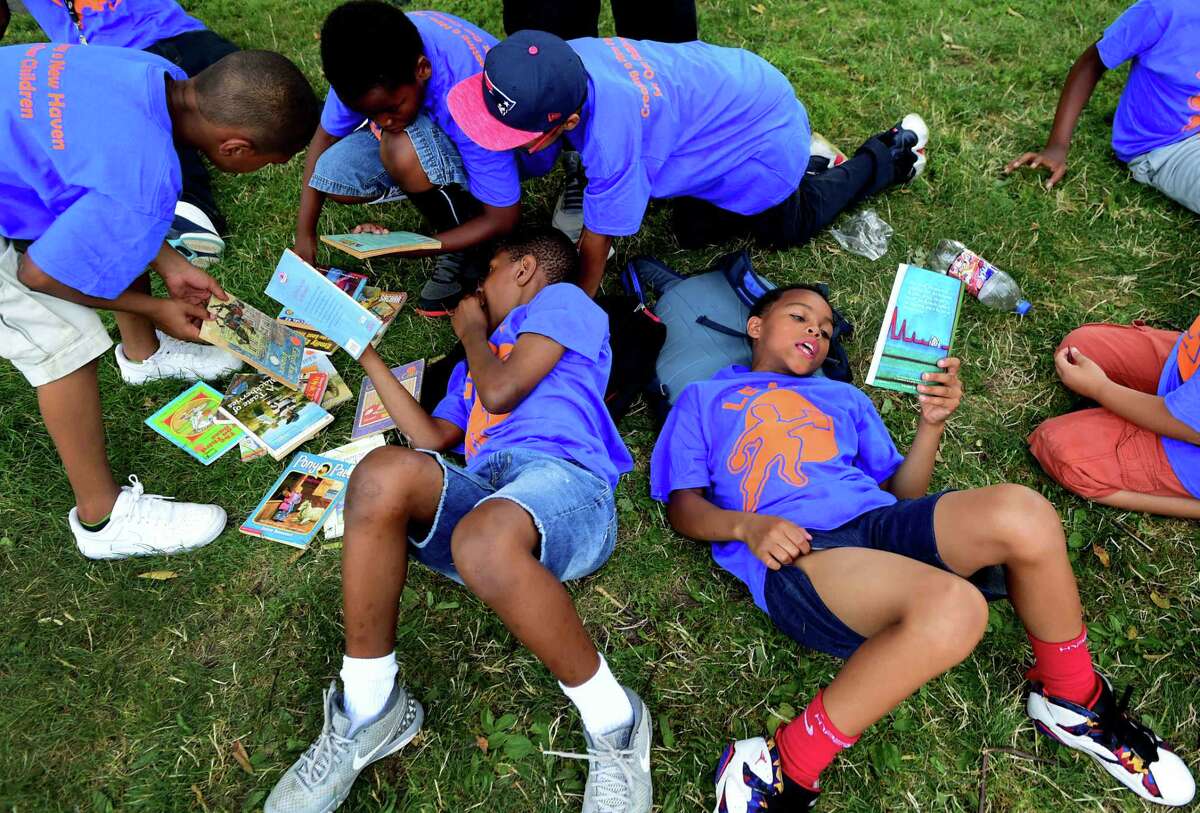 (Peter Hvizdak - New Haven Register) Tyere Montgomery, 9, of New Haven, laying on his back, left, and James Johnson, 10, of East Haven, next to him with their fellow campers as they search to find a free book to take home during the LEAP Read-In on the New Haven Green Friday, July 22, 2016 where volunteers read age-appropriate books aloud to small groups of children and their counselors. The Read-In encourages active reading in children. LEAP, Leadership, Education, and Athletics in Partnership, Inc. is one of New Haven's oldest youth services programs.