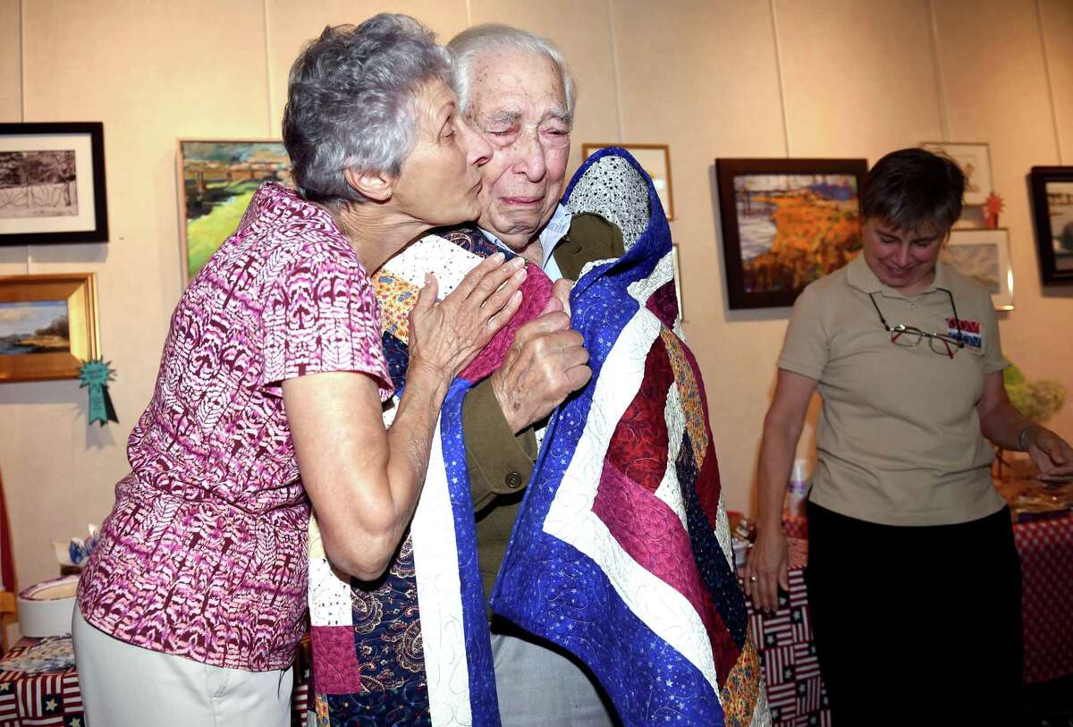 (Arnold Gold-New Haven Register) Mary Ann Lotto (left) gives Bill Brody of Branford a kiss as he is presented with a quilt made by Lotto during a Quilts of Valor ceremony at the Willoughby Wallace Memorial Library in Branford on 8/23/2016. Brody served in the Army Corp of Engineers during World War II. Lotto is part of the Willoughby Wallace Library Quilters. At right is Jane Dougherty, Connecticut Co-Coordinator for the Quilts of Valor Foundation.