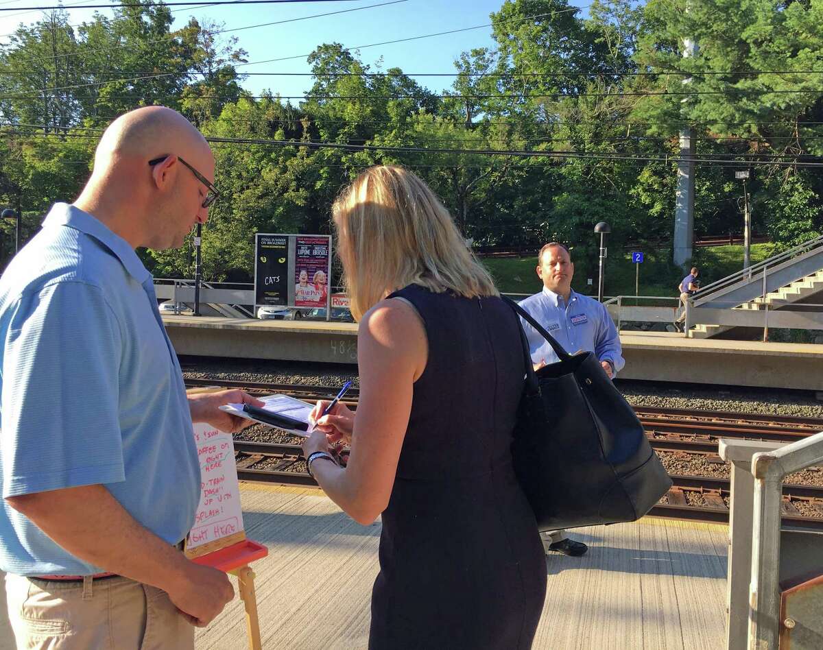 At Riverside train station Monday morning, Jason Auerbach (left) collected a signature from a voter for his pro-charter change petition while Peter Bernstein (right) waited with a petition to get on the Board of Education ballot in November. Both men are Republican school board candidates.