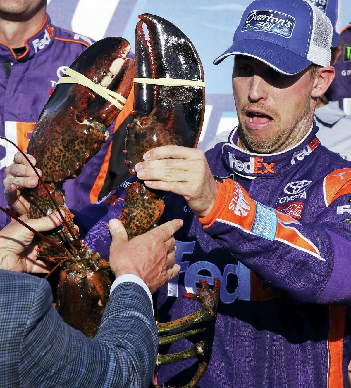 Driver Denny Hamlin reacts as he is handed a lobster after winning at the New Hampshire Motor Speedway in Loudon, N.H., on Sunday.