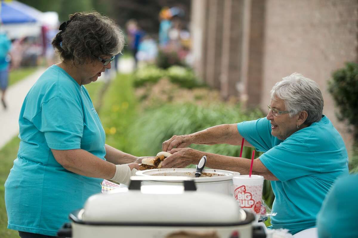 Leona Seamster, right, serves food to Barb Frankling during First Baptist Church's neighborhood block party on Wednesday, August 2, 2017.