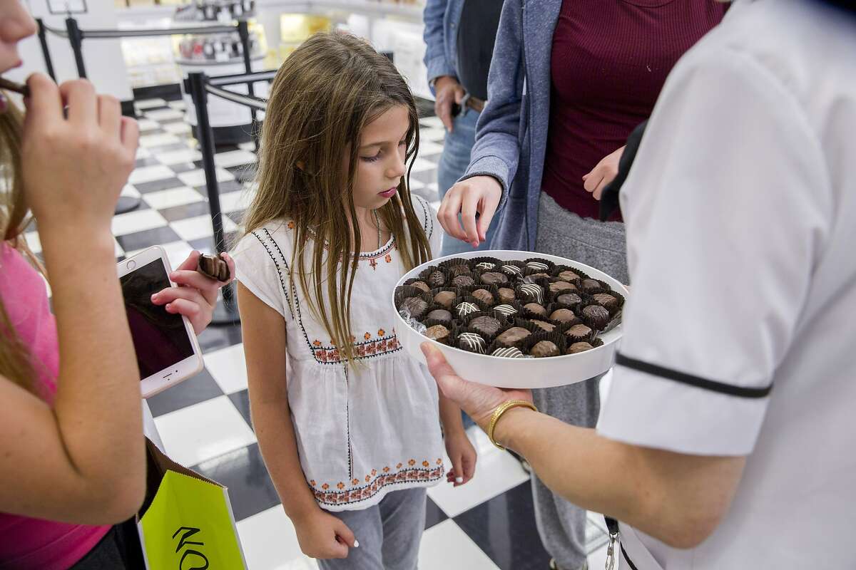 India Sanor, 8, checks out the chocolate sample from Jeannie Jew at See's Candies inside the Stonestown Galleria.