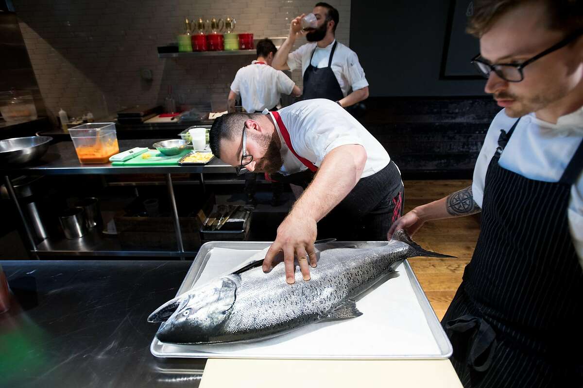 Lazy Bear chef de cuisine Chris Johnson examines a king salmon on Wednesday, Aug. 2, 2017, in San Francisco. AT right is sous chef Matt Hanley.