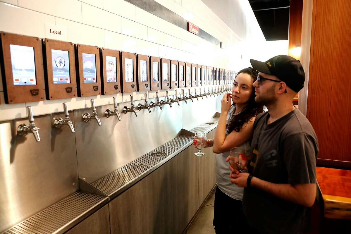 Mitchell and Jasmine Conley look over the selections of 70 beers on tap at Pour Taproom as seen on Thurs. July 27, 2017 in Santa Cruz, Ca.