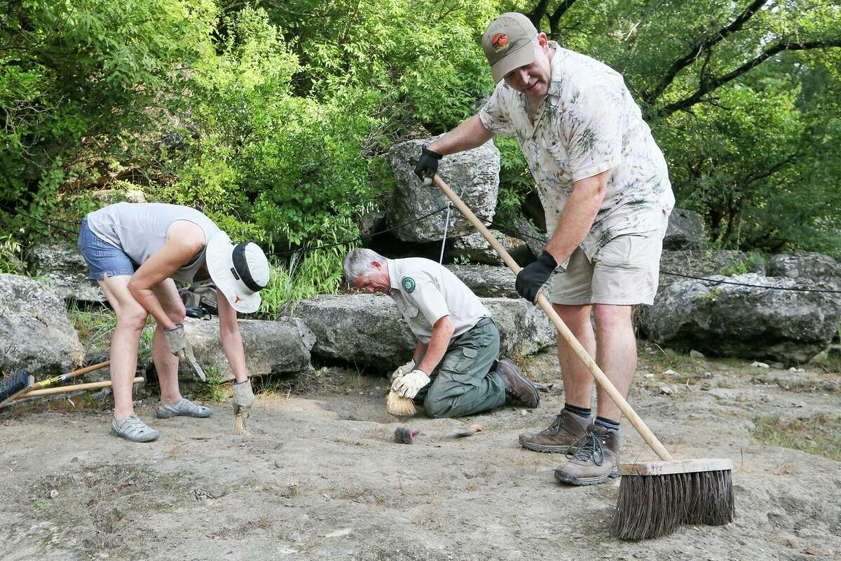 Thomas Adams, curator of paleontology and geology at the Witte Museum, cleans dinosaur tracks on the lower trackway at Government Canyon State Natural Area with park interpreter John Koepke and Debi Weissling in 2017. Adams is working to expand the museum’s paleontology program, including working with students and spending more time in the field.