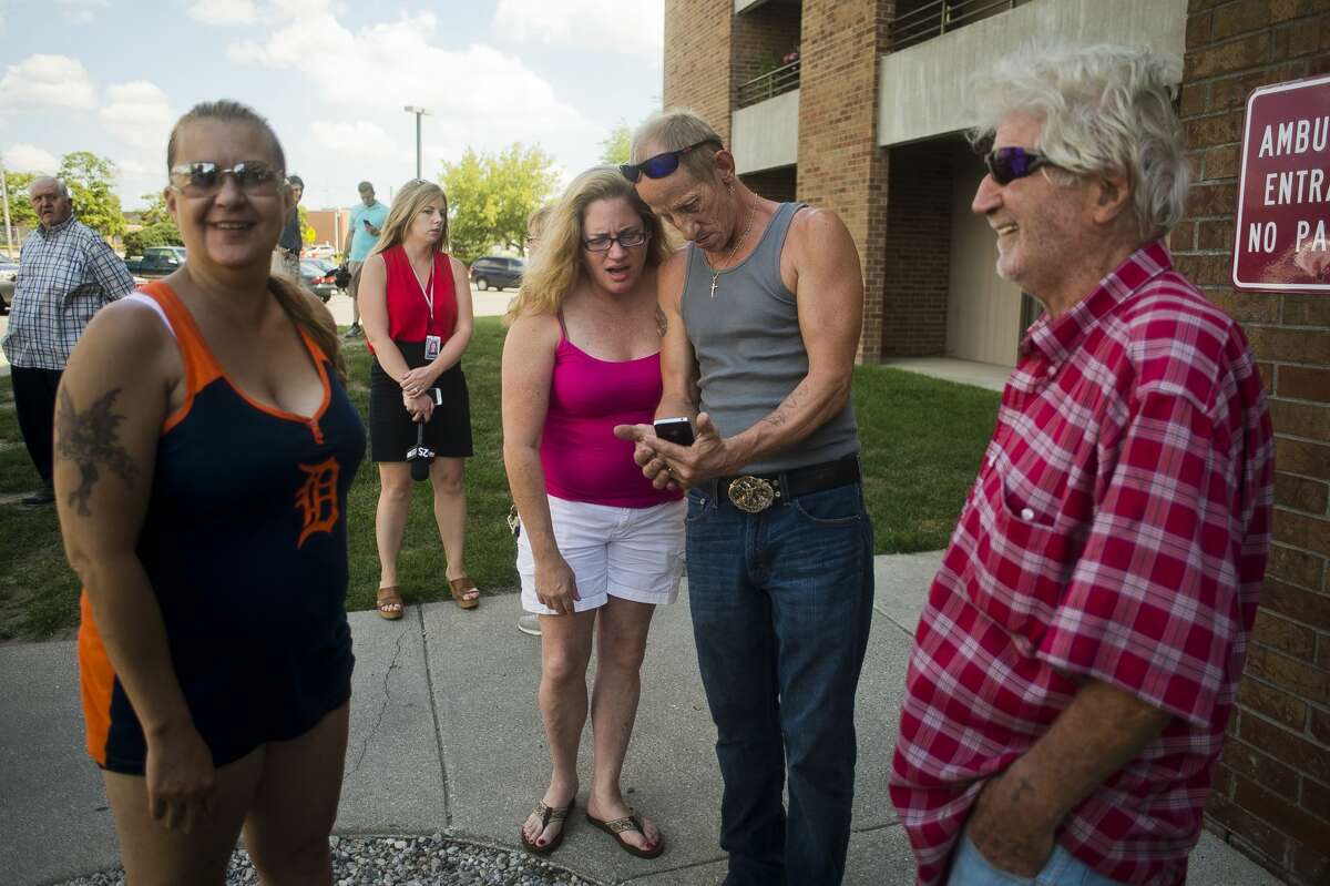 From left, Tonia Bauknecht, Kelly Stout, Todd Stout and Gil Hansen look at photos of Hansen's apartment, which caught fire on Monday inside Greenhill Apartment complex, as they wait to go back into their apartments and retrieve belongings on Tuesday, August 1, 2017. The cause of the fire, which started in Hansen's 8th floor apartment, was deemed unintentional, Fire Chief Chris Coughlin said.