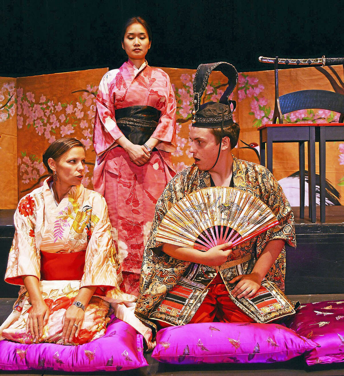 Shannon Kessler Dooley (Madama Butterfly), Evanna Lai (Suzuki), and Zachary Johnson (Prince Yamadori) kneeling, sing and learn the formal use a Japanese fan.