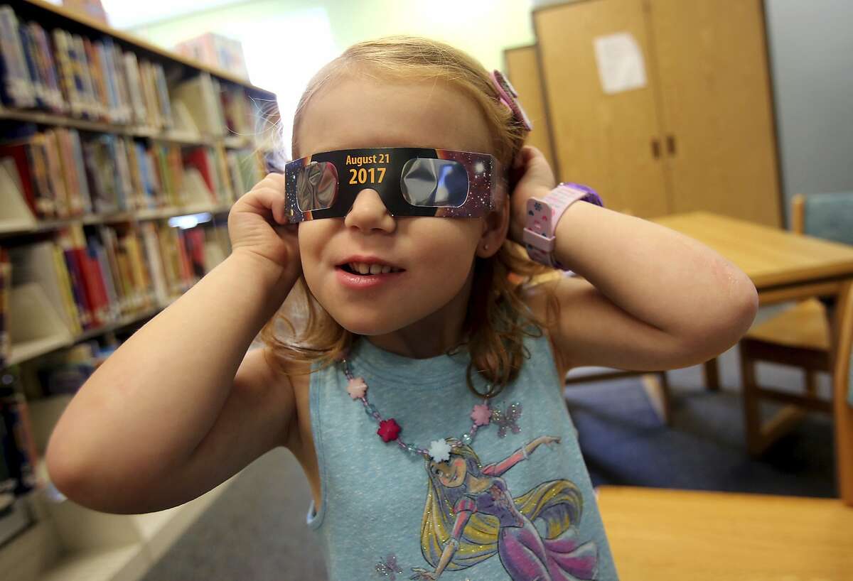 Emmalyn Johnson, 3, tries on her free pair of eclipse glasses at Mauney Memorial Library in Kings Mountain, N.C., Wednesday, Aug. 2, 2017. Glasses are being given away at the library for free while supplies last ahead of the big event on August 21. (Brittany Randolph/The Star via AP)