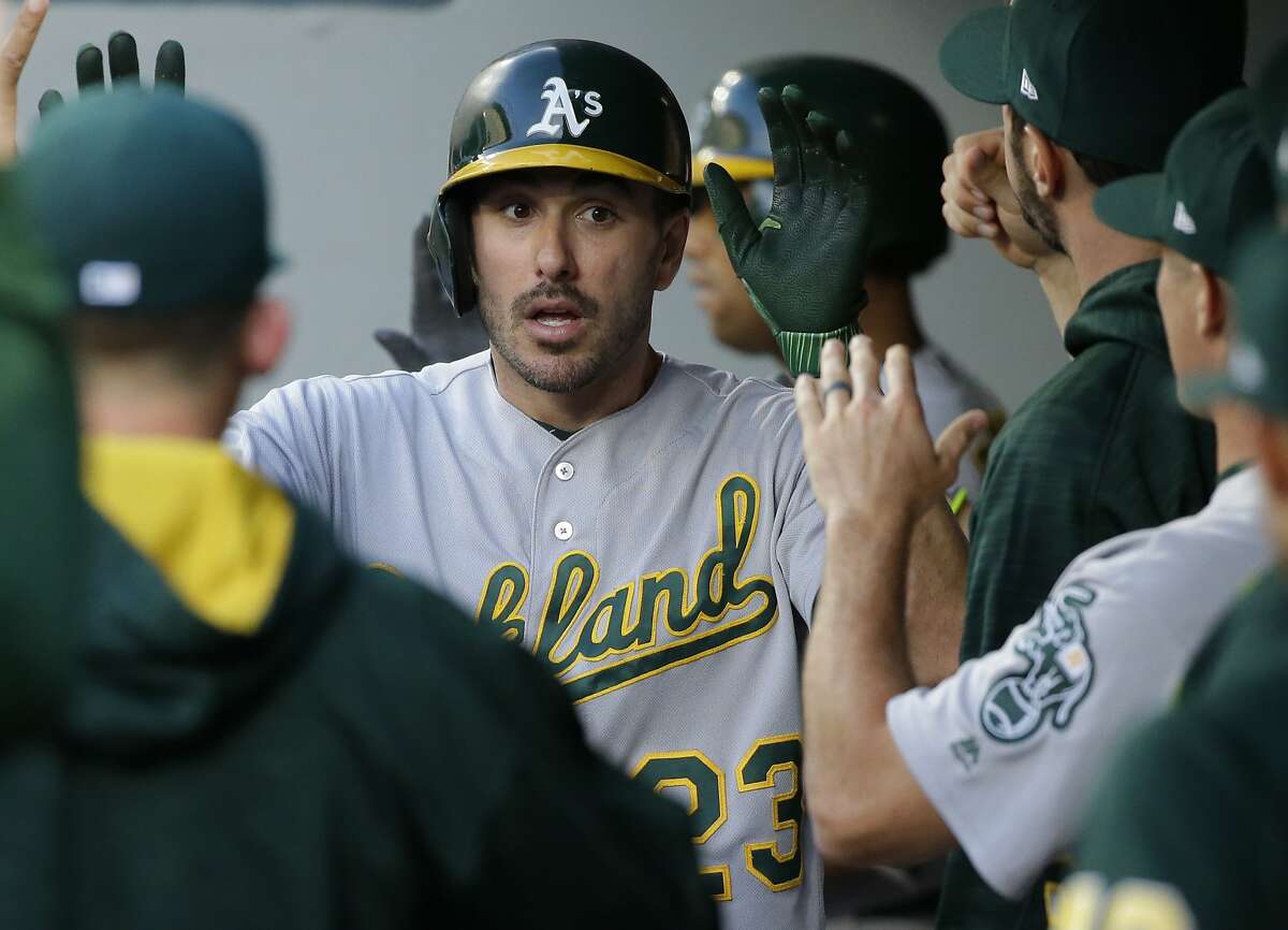 Oakland Athletics' Matt Joyce is greeted in the dugout after he scored on a double by Marcus Semien during the third inning of the team's baseball game against the Seattle Mariners, Friday, July 7, 2017, in Seattle. 