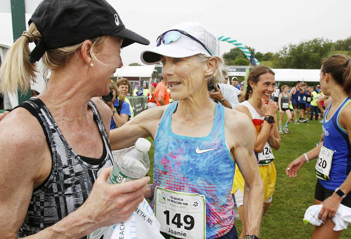 Former Olympian Joan Benoit Samuelson, right, is congratulated by Deena Kastor, winner of bronze medal in the women's marathon at the 2004 Olympics in Athens, Greece, after finishing the 20th annual TD Beach To Beacon 10K road race Saturday, Aug. 5, 2017 in Cape Elizabeth, Maine. (AP Photo/Joel Page)