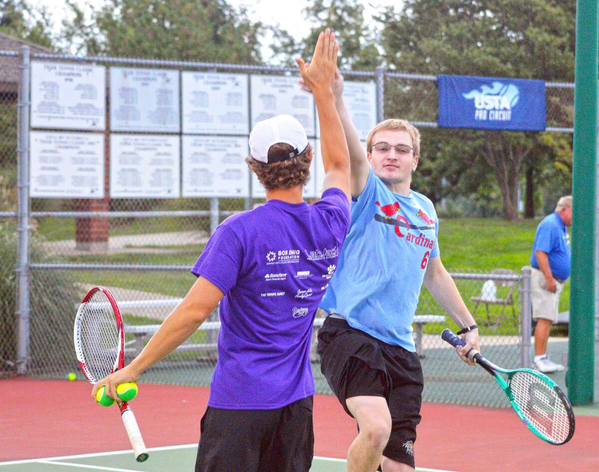 Michael Bugger, right, exchanges a high five with former Edwardsville player Jack Desse on Sunday during the sixth annual Mitch n’ Friends night at the EHS Tennis Center.