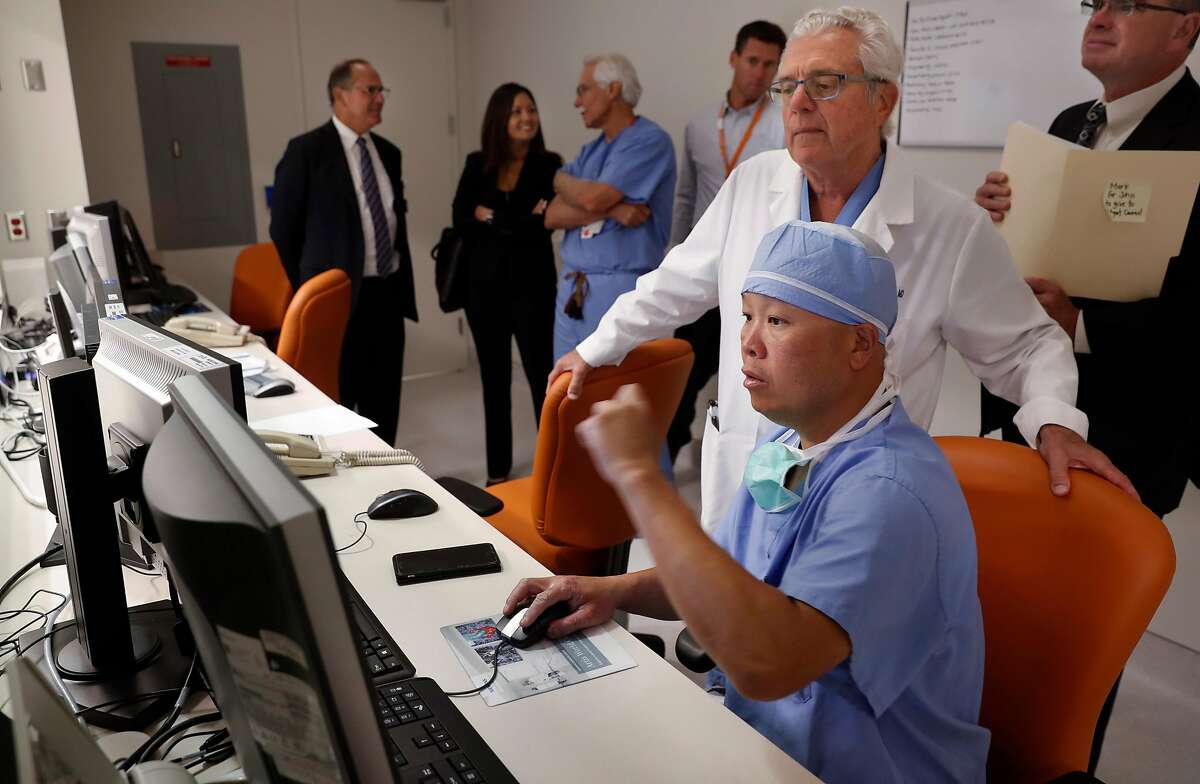 Dr. Robert Murray, chief medical officer at St. Mary's looks over the shoulder of Alex Chan, lead cardiovascular technician during a demonstration inside the control room of the cardiology laboratory at St. Mary's Medical Center in San Francisco, Ca., on Mon. August 7, 2017. Cardiology is one of a handful of practice areas where UCSF will be taking its resources and bringing it over to Dignity.