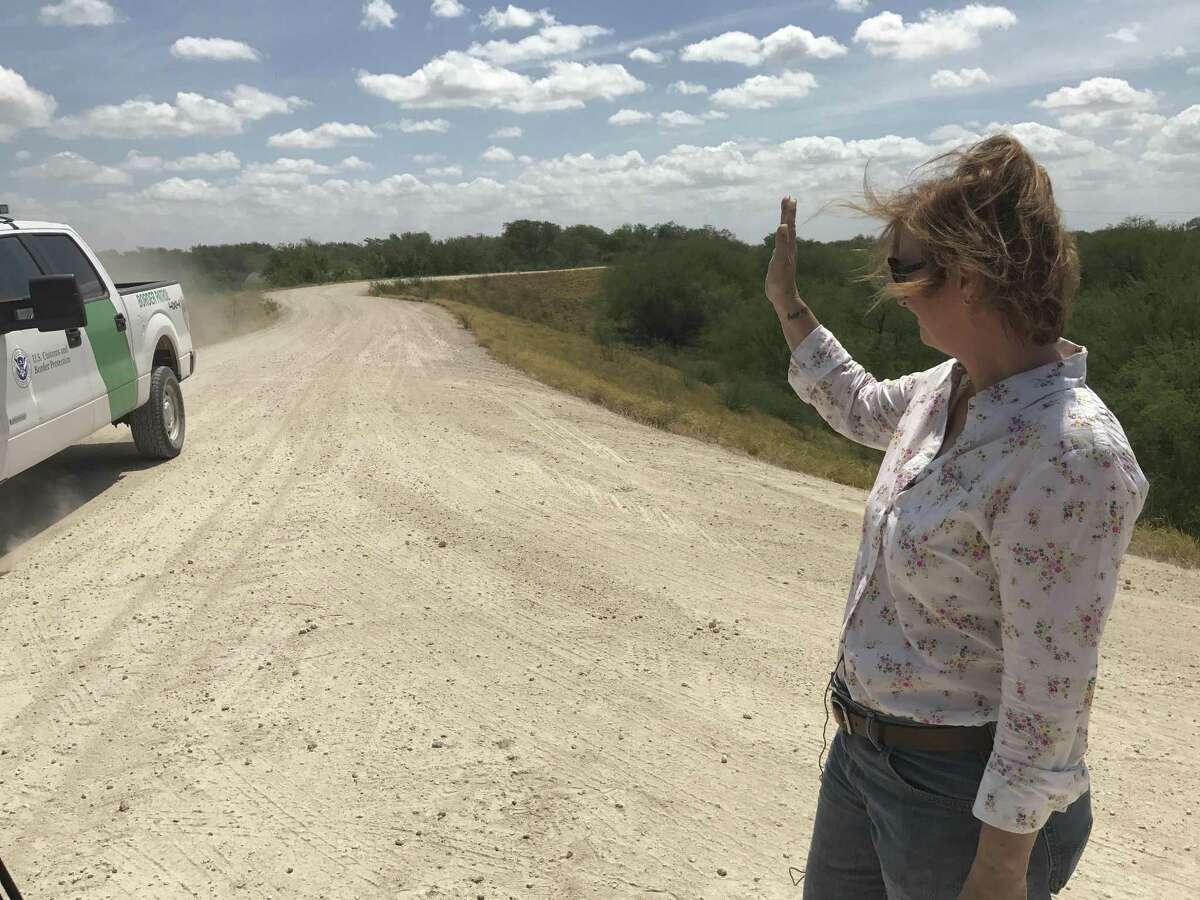 Marianna Trevino-Wright, the executive director of the National Butterfly Center, stands on the levee being studied for a section of President Donald Trump's border wall, and waves to a Border Patrol agent.