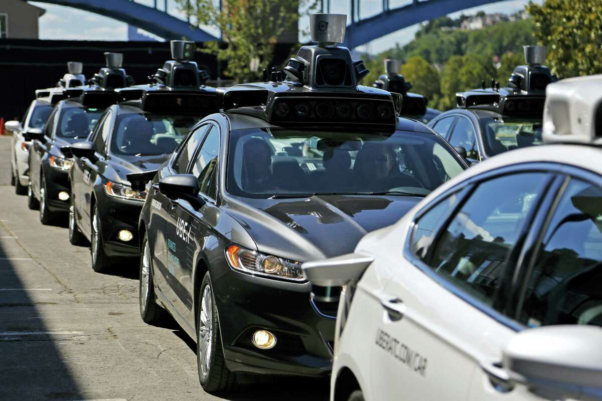 FILE - In this Monday, Sept. 12, 2016, file photo, a group of self-driving Uber vehicles position themselves to take journalists on rides during a media preview at Uber's Advanced Technologies Center in Pittsburgh. U.S. President Donald Trump‚Äôs economic plans are nothing if not ambitious, including his vision of creating 25 million jobs over 10 years. However, the widespread use of robots and automation by companies has increasingly allowed businesses to operate with fewer workers. For example, Uber is experimenting with self-driving cars, and restaurant chains like Eatsa can now serve lunch and dinner through an automated order-and-payment system, and no cashiers or servers are necessary. (AP Photo/Gene J. Puskar, File)