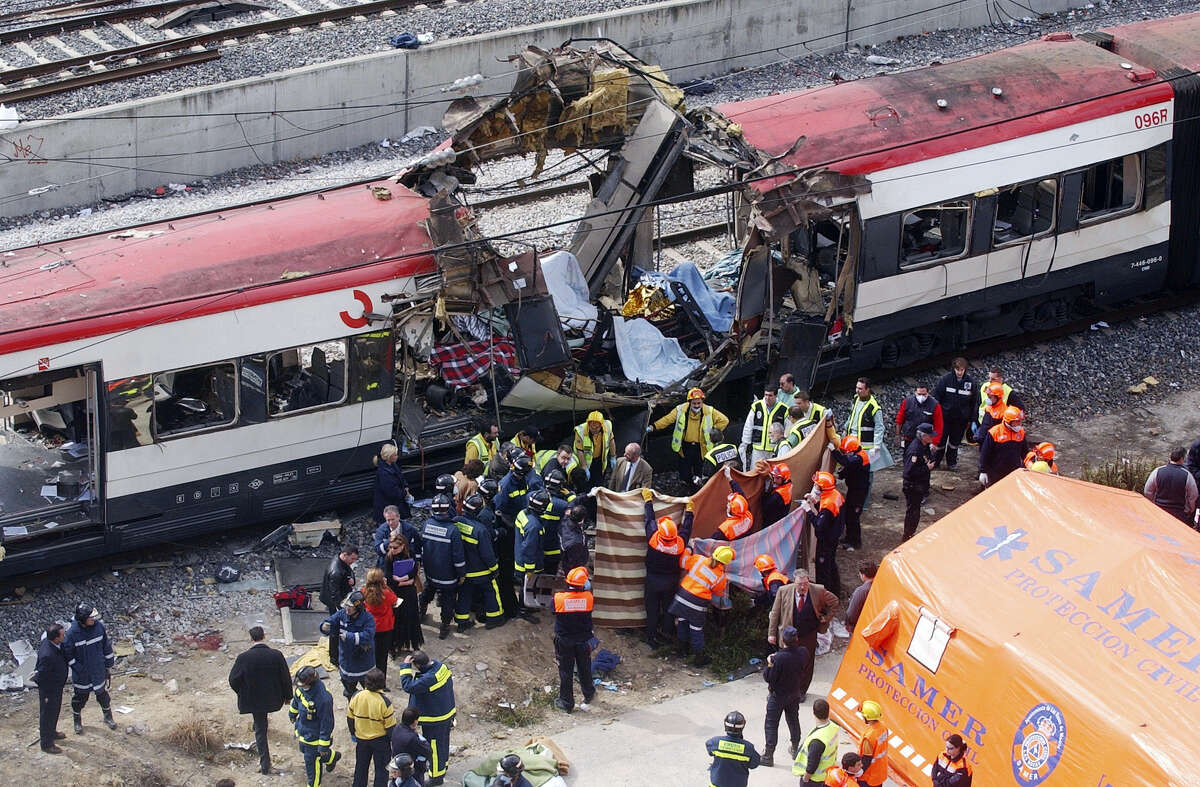 FILE - In this March 11, 2004 file photo, rescue workers cover up bodies alongside a bomb-damaged passenger train, following a number of explosions in Madrid, Spain, killing 191 people and wounding more than 500 in Spain's worst terrorist attack ever. The deadly vehicle and knife attack Saturday, June 3, 2017, on London Bridge and in nearby Borough Market is the latest attack in Europe in recent years. (AP Photo/Paul White, File)