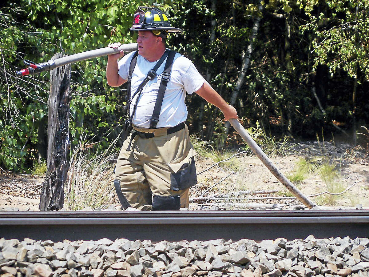 (Wes Duplantier/The New Haven Register)Firefighters from North Haven and Hamden worked for more than an hour Monday to contain a brush fire along the railroad tracks near part of Washington Avenue in North Haven.
