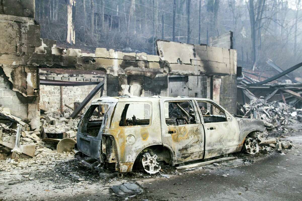 A scorched vehicle sits next to a burned out building in Gatlinburg, Tenn., on Tuesday, Nov. 29, 2016. The fatal fires swept over the tourist town the night before, causing widespread damage. (AP Photo/Erik Schelzig)