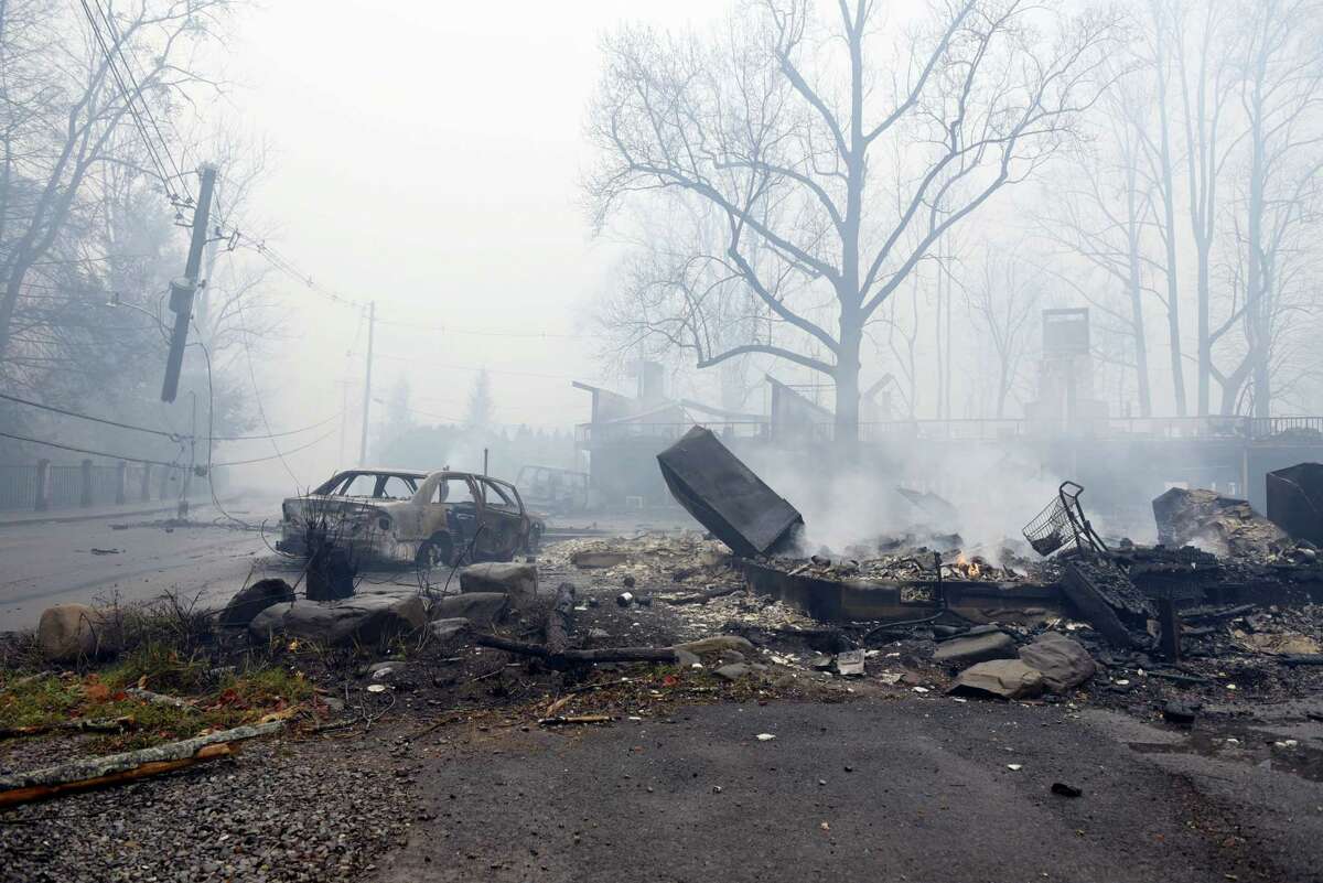 A structure and vehicle are damaged from the wildfires around Gatlinburg, Tenn., on Tuesday, Nov. 29, 2016. Rain had begun to fall in some areas, but experts predicted it would not be enough to end the relentless drought that has spread across several Southern states and provided fuel for fires now burning for weeks in states including Tennessee, Georgia and North Carolina. (Michael Patrick/Knoxville News Sentinel via AP)