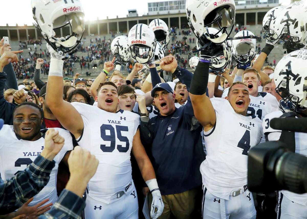 Yale head coach Tony Reno, center, celebrates with his team including Tim Dawson II (95) and Sebastian Little after their 21-14 win over Harvard in an NCAA football game at Harvard Stadium in Cambridge, Mass. Saturday, Nov. 19, 2016. (AP Photo/Winslow Townson)