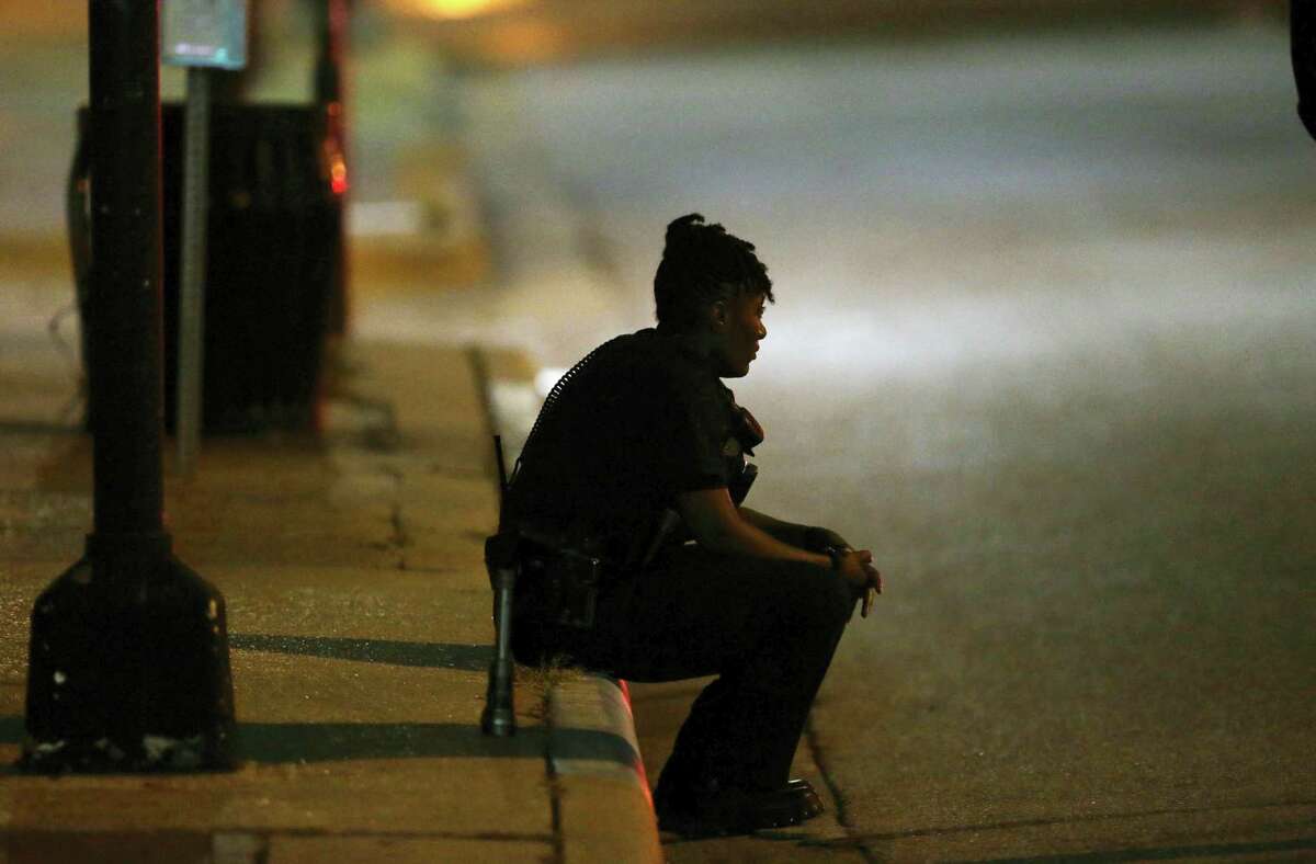A Dallas police officer, who did not wish to be identified, takes a moment as she guards an intersection in the early morning after a shooting in downtown Dallas, Friday, July 8, 2016. Snipers opened fire on police officers in the heart of Dallas during protests over two recent fatal police shootings of black men. (AP Photo/LM Otero)
