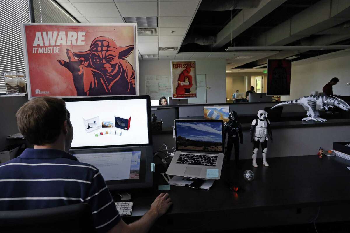 In this July 24, 2015 photo, an employee at Sphero, a fast-growing toy robotics company, works surrounded by Star Wars toys and posters, at the company headquarters in Boulder, Colo. The company has collaborated with Lucasfilm-parent Disney to develop the BB-8, a droid character which will be featured in ìStar Wars: Episode VII - The Force Awakens.î (AP Photo/Brennan Linsley)