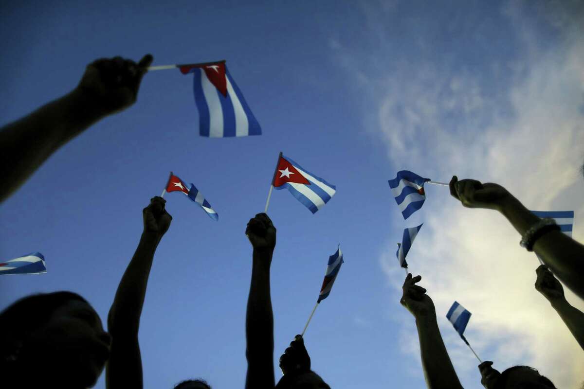People holds up Cuban flags before a mass rally honoring Fidel Castro at the Antonio Maceo plaza in Santiago, Cuba, Saturday, Dec. 3, 2016. Castro's ashes arrived in Santiago to be buried after a four-day journey across Cuba from Havana. (AP Photo/Natacha Pisarenko)