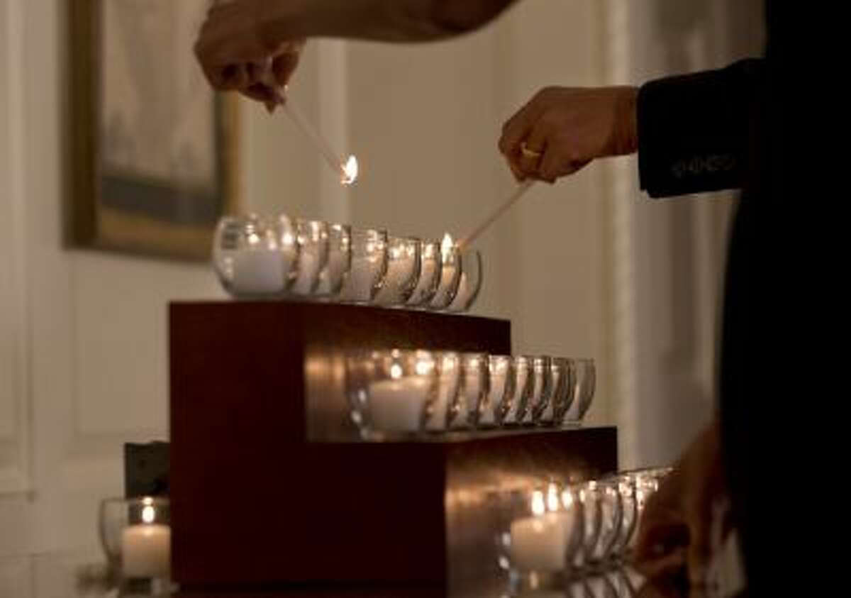 Twenty-six candles are lit by President Barack Obama and first lady Michelle Obama in honor of the Newtown shooting victims, in the Map Room of the White House in Washington, Saturday, Dec. 14, 2013, on the one year anniversary of the massacre.