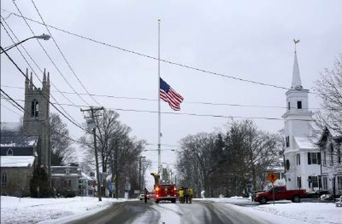 On the first anniversary of the Sandy Hook massacre, firefighters lower the town's flag on Main Street to half-staff in honor of the victims, Saturday, Dec. 14, 2013, in Newtown, Conn.