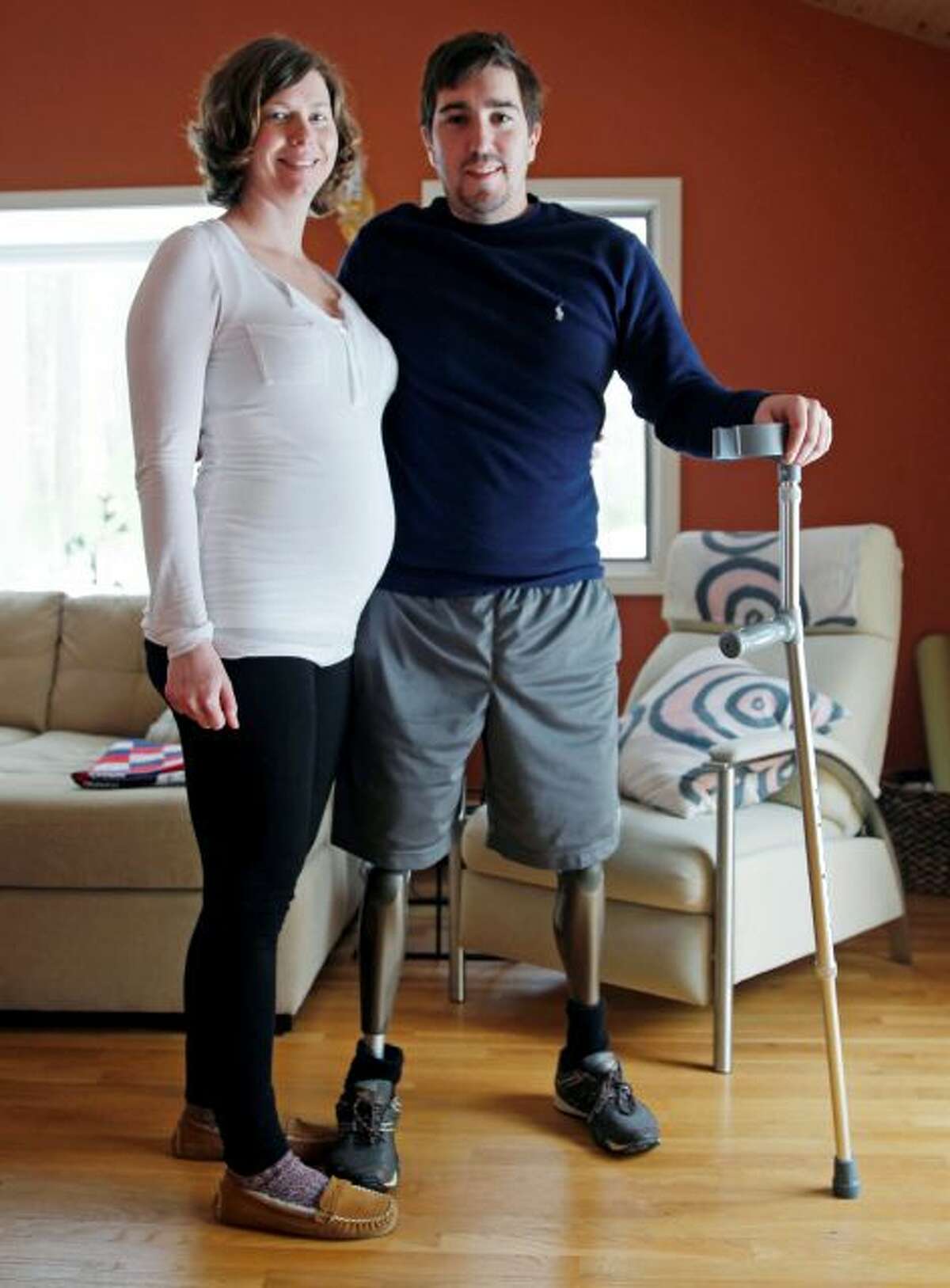 Jeff Bauman, who lost both legs in the Boston Marathon bombings, then helped authorities identify the suspects, poses with his expectant fiancé, Erin Hurley, their home in Carlisle, Mass., Friday, March 14, 2014. According to Bauman, the baby is due July 14. They don't know if it's a boy or a girl, and they want it to be a surprise. The two were engaged in February. (AP Photo/Charles Krupa)