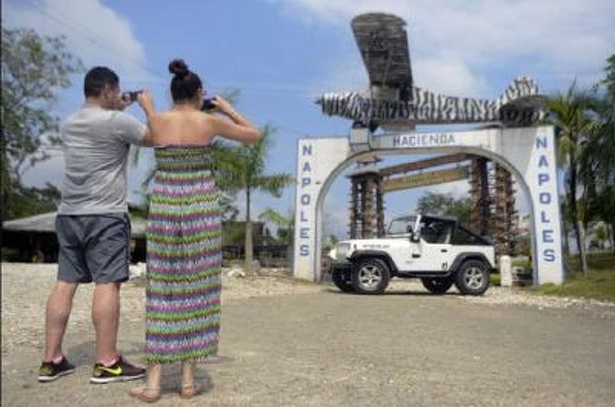 Tourists take snapshots of the single-engine plane Colombian drug lord Pablo Escobar used to send his first cocaine shipment to the U.S. It hangs above the entrance to Hacienda Napoles.